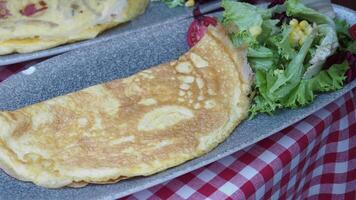 A Savory Omelette Accompanied by a Fresh and Colorful Salad Served on a Rustic Table video
