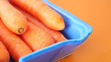 Fresh Organic Carrots Stored in a Blue Container Against a Vibrant and Colorful Background video