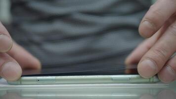 A pair of hands meticulously inspecting a smartphone screen to ensure complete flatness and quality video