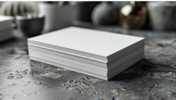 A stack of white business cards sits on a grey surface photo
