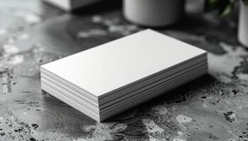 A stack of white business cards sits on a grey surface photo