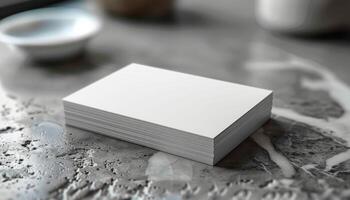 A stack of white business cards sits on a marble countertop photo