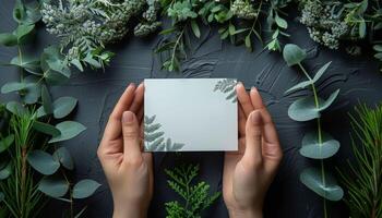 A person holds a white card with a leaf design on it photo
