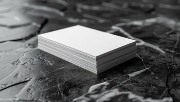 A stack of white business cards sits on a black surface photo