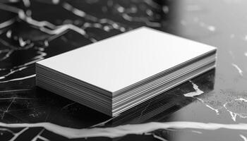 A stack of white business cards sits on a black marble countertop photo