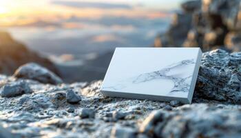 A white box with a marble design sits on a rocky surface photo