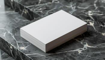 A stack of white business cards sits on a marble countertop photo