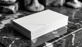 A stack of white business cards sits on a marble countertop photo