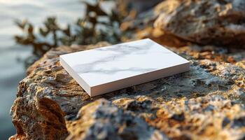 A white box with a marble design sits on a rock by a body of water photo