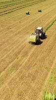 Agricultural process of modern machinery in the field. Aerial view of grassland during harvesting on a sunny day in countryside. Vertical video