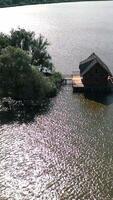Small island and a house in the middle of the river. Aerial view of beautiful green island surrounded by water. Camera moves round. Vertical video