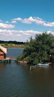 Green island and a house on water. Aerial view of beautiful island in the middle of a lake surrounded by water on the natural background. Vertical video