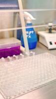 New small test tubes laying out on a plastic rack. Female hand in protective glove holding tweezers while putting sterile vials on a support in the laboratory. Vertical video