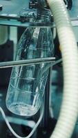 Close-up process of pouring milk into plastic bottle. Robotic machine for bottling milk in a dairy factory. Vertical video