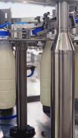 Robotic dairy plant indoors. Automatic equipment for covering plastic bottles with milk in a modern factory. Process of putting plastic lids on bottles. Vertical video