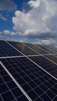 poder estação. solar painéis debaixo a azul céu com branco nuvens. alternativo fonte do eletricidade em solar energia Fazenda. fonte do ecológico renovável energia. vertical video