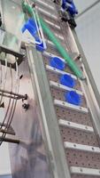 Automatic technology in a dairy factory. Modernized equipment in a plant. Conveyor line rising up with plastic lids for further packaging. Slow motion. Vertical video