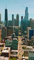 Long street of Chicago with busy traffic passing through skyscrapers. Amazing architecture at backdrop of blue sky. Vertical video