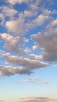 Formation of cumulus cloudscape in the atmosphere. Low angle timelapse of little soft clouds in the sky. Vertical video