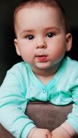 Serious interested kid standing on the chair looks around. Curious baby studying surrounding leaning on a chair back. Low angle view. Vertical video
