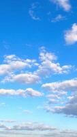 Big and separate little clouds float in the amazing blue sky. Timelapse of light fluffy clouds moving in the horizon. Vertical video
