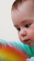 Baby boy with adorable plump cheeks looks down on a toy. Portrait of a cute child interested in play. Close up. Vertical video