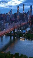 New York in lights at evening time. Beautiful Queensboro Bridge with green park and parking lot under. View from top. Vertical video