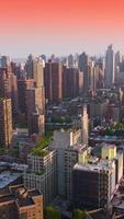 Densely built Manhattan area in New York. Beautiful buildings of diverse height and design at the backdrop of pink sky. View from above. Vertical video