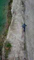 Man walking along lake. Aerial view of man walking along lake with forest Vertical video
