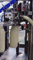 Robotic process for filling bottles with milk in a factory. Milk is pouring into plastic bottles by a special automatic equipment in a modern dairy plant. Vertical video