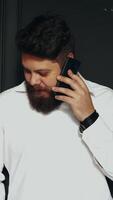 Man reading message on smartphone. Indoor shot of young man reading text message on mobile phone in studio Vertical video