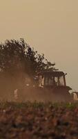 Tractor working on the field in the evening. Agricultural works on the natural background in the countryside. Vertical video