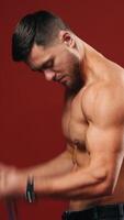 Male flexing his muscles. Muscular model young man on background. Vertical video