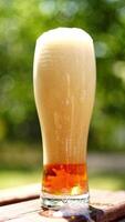 Full glass of white foam from beer. Process of becoming beer beverage from foam in the glass on blurred background. Bubbles and foam in beer glass. Vertical video