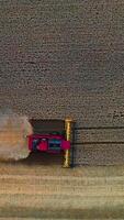 Aerial view on the combine working on the large wheat field. Grain harvesting equipment in the field. Vertical video