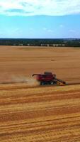 Aerial view on the combine working on the large wheat field. Grain harvesting equipment in the field. Vertical video