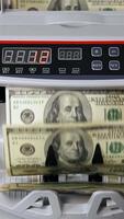 USD on money counting machine. Woman putting money into counting machine Vertical video