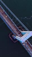 Massive huge bridge over the deep river. View from top on the bridge with transport moving quickly. Vertical video