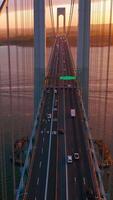 Multi-lane road with cars going through the bridge. View from top on the Bronx-Whitestone bridge at the backdrop of East River. Vertical video