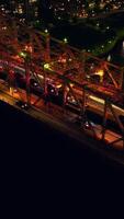 Traffic jams on the big bridge at night time. Launch going under the bridge along dark river. Top view. Vertical video