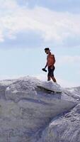 Man on a top of a mountain. Young man standing on cliffs edge of top of the mountain Vertical video