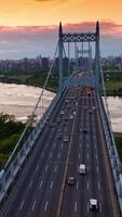 Busy traffic on multi-lane roads of Robert F. Kennedy Bridge. Stadium and car park on both sides of bridge. Cityscape at backdrop. Vertical video