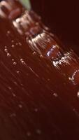 Candies come out from the flow of chocolate. Sweets deepened in a thick layer of chocolate. Close up. Vertical video
