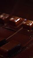 Bars of sweets poured with chocolate. Chocolate bars move along conveyor belt at confectionery factory for the production of sweets. Vertical video