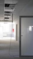 Recently built premises with unfinished inside works. Light system in the process of installation. Wires hanging from the ceiling. Vertical video