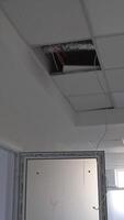 White corridor in a newly-built building. Focus on the unfinished pieces of ceiling cover. Open doors lock close up. Vertical video