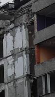 Big hydraulic claw grasps the concrete floor of the destroyed house. Excavator crasher reaches high to break the walls and floors of the ruined building. Vertical video