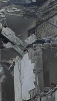 Breaking concrete walls and floors with the help of machinery. Dusty area of destruction site. Powerful claw ruins the house. View from below. Vertical video