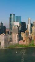Stunning Manhattan island with shiny skyscrapers reflecting in the water. Daytime perspective on New York from river. Vertical video