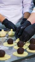 Three confectioners make cookie desserts. Manufacturing handmade sweets with stuffing at food factory. Close up. Vertical video